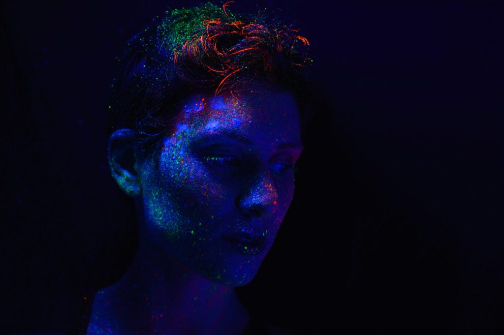 a woman in a dark room with a blue and green glow on her face
